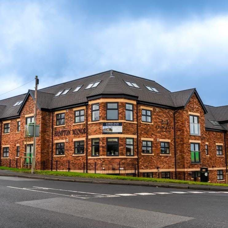 The front of Hampton Manor care home, a four storey red brick building with its name on the wall